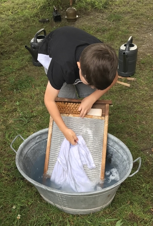 Ein Schüler wäscht auf einem Waschbrett sein Handtuch